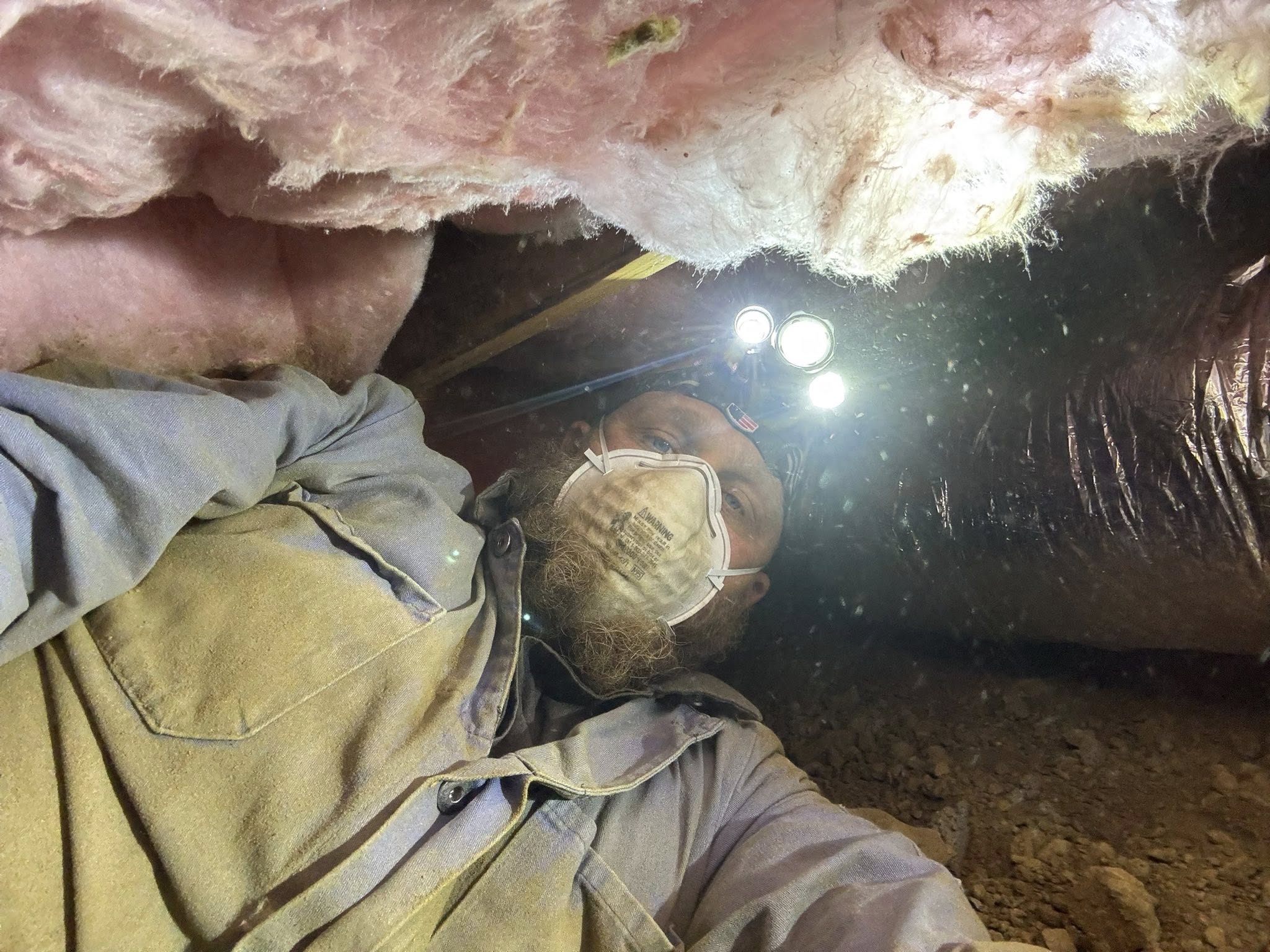 Adam Mayer working in crawlspace with headlamp